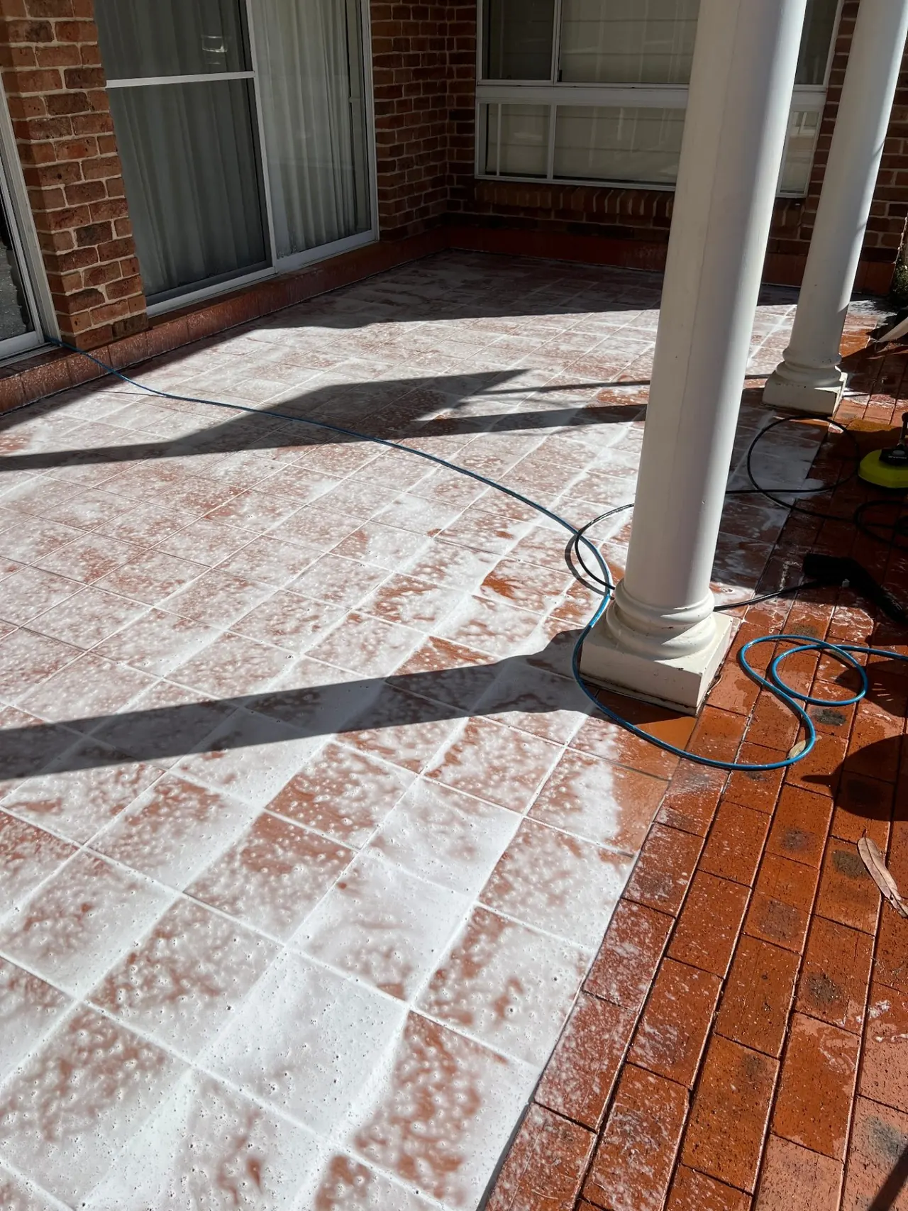Tiled patio being foamed and pressure washed clean